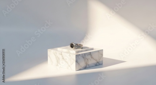 Silver ring displayed on white marble block with sunlight.