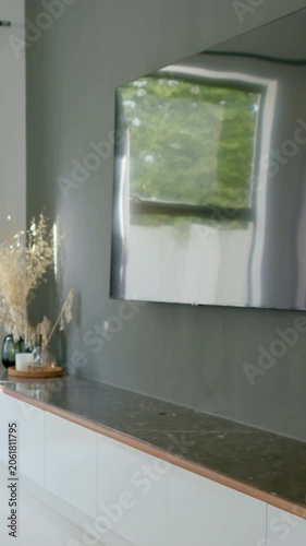 Vertical video: Panning camera revealing mirrored panel at right, exposing low cabinet and vases