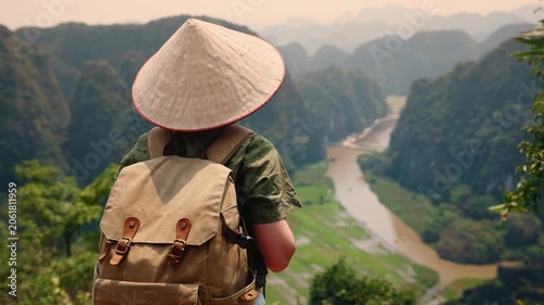 Asian young adult exploring scenic Ninh Binh Vietnam with backpack in traditional hat, concept trip travel.