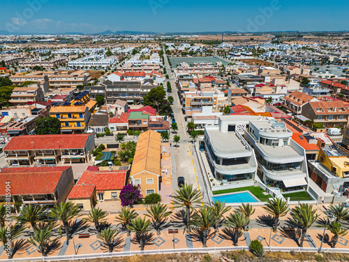 Aerial view of coastal Torre de la Horadada town with residential buildings, palm trees seafront promenade. Mediterranean travel and real estate development concept for tourism. Costa Blanca, Spain