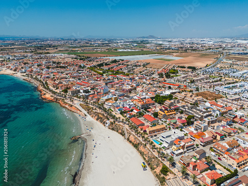 Aerial view of Torre de la Horadada coastal town with sandy beach and residential buildings along Mediterranean Sea coast. Tourism and vacation destination. Costa Blanca, Spain