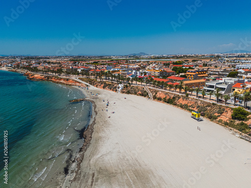 Aerial view vibrant Mediterranean coastal Torre de la Horadada town with sandy beaches and blue Mediterranean Sea. Coastal tourism, travel. Costa Blanca, Alicante province, Spain