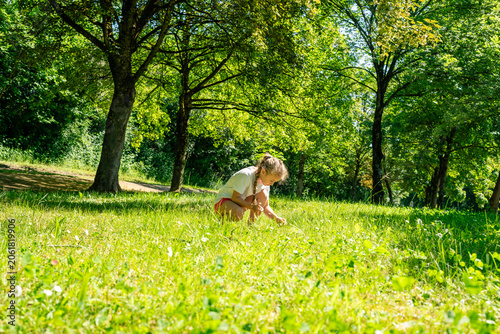 Quadro su tela Young girl alone in a sunny public park surrounded by lush trees, concept of ind