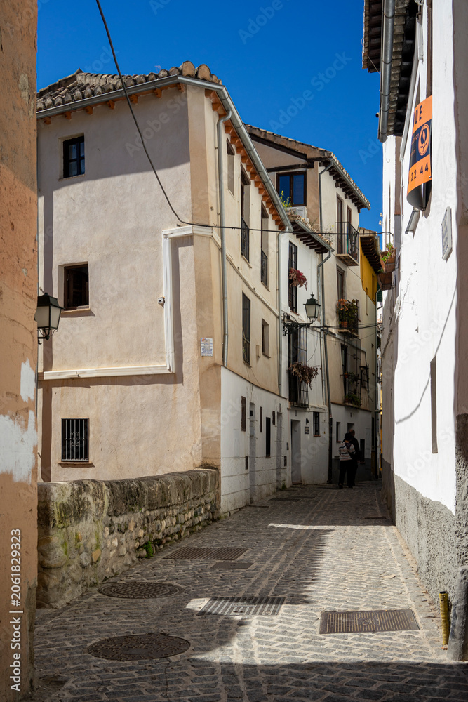 Obraz premium Narrow urban historic street in Granada, Spain on a sunny day