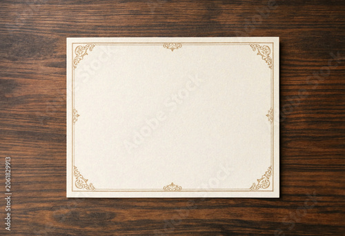 Blank certificate template with ornate gold border on wooden background
