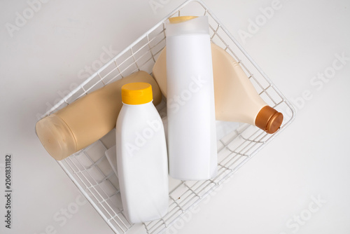 Variety of empty cosmetic plastic bottles neatly arranged in a white metal wire basket, waste management and recycling concept