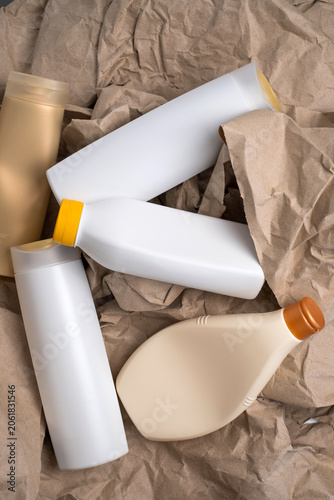 Collection of assorted empty plastic cosmetic bottles arranged on crumpled brown kraft paper, recycling concept