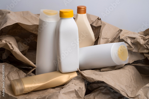 Collection of assorted empty plastic cosmetic bottles arranged on crumpled brown kraft paper, recycling concept