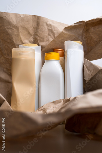 Collection of assorted empty plastic cosmetic bottles arranged on crumpled brown kraft paper, recycling concept