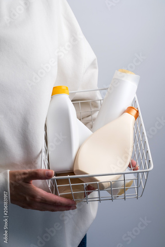 Person holding a basket full of plastic cosmetic bottles, plastic waste and recycling concept