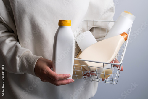 Person holding a basket full of plastic cosmetic bottles, plastic waste and recycling concept