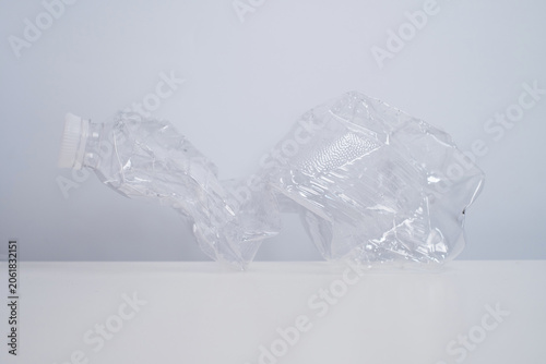 Single crushed clear plastic bottle on a clean white surface, plastic waste and recycling concept
