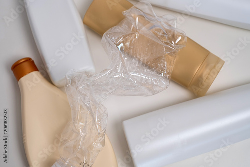 Crushed plastic bottle on top of assorted cosmetic containers, plastic waste and recycling concept