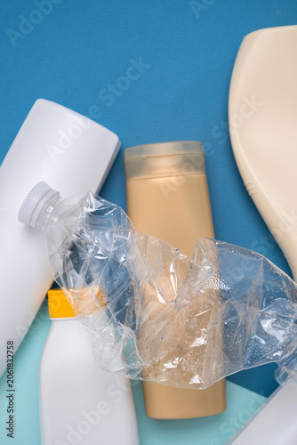 Crushed plastic bottle on top of assorted cosmetic containers, plastic waste and recycling concept