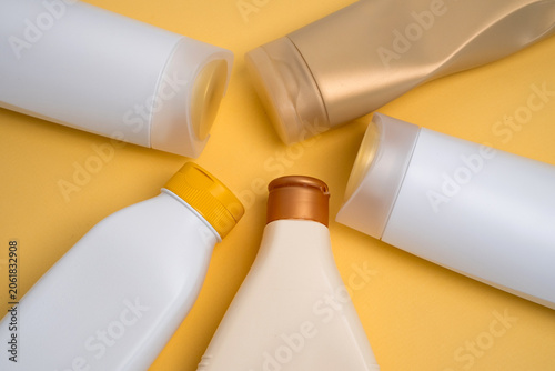 Assorted cosmetic bottles and containers arranged on a vibrant yellow background, skincare and beauty product concept