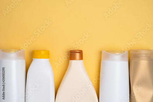 Assorted cosmetic bottles and containers arranged on a vibrant yellow background, skincare and beauty product concept