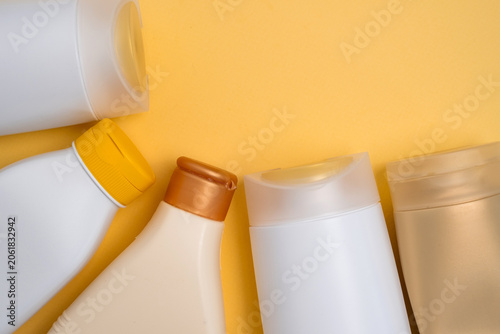 Assorted cosmetic bottles and containers arranged on a vibrant yellow background, skincare and beauty product concept
