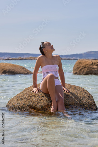 Teenage girl sitting on a beach rock