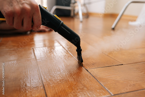 Foto Close-up of person cleaning and sanitizing floor with a steam machine, maintaining household cleanliness and effectively eliminating grime from tiled surface with hot steam