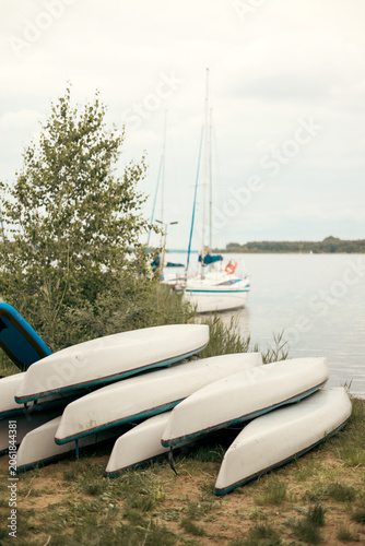 Sailing yachts with lowered sails moored beside a pier on a peaceful lake