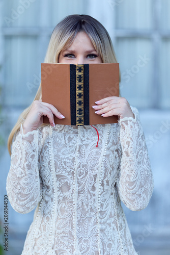 Woman hiding behind a book outdoors