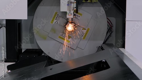 Automatic cnc laser cutting machine is processing cylindrical metal workpiece with many sparks at factory, plant: slow motion. Metalworking, industrial, manufacturing and equipment concept