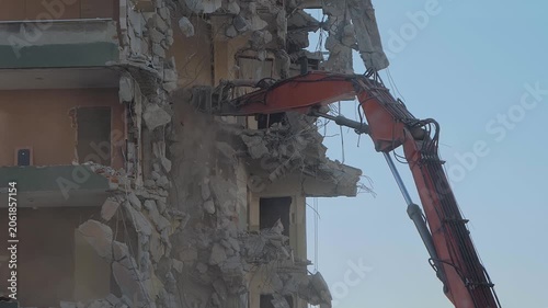 Slow motion: demolition of building, excavator with hydraulic crusher is tearing down the old typical Turkish multi-storey apartment, residential building in Istanbul, Turkey
