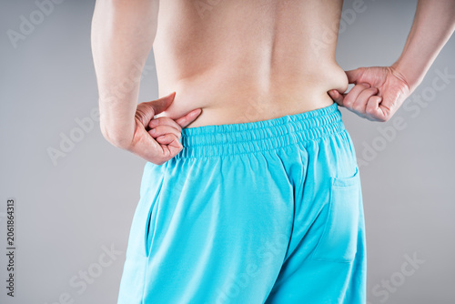 Fotografie Man pinching his love handles on the lower back