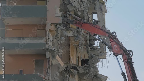 Demolition of building, excavator with hydraulic crusher is tearing down the old typical Turkish multi-storey apartment, residential building in Istanbul, Turkey: slow motion