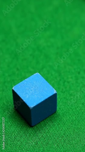 Small plastic cube on bright green textured background