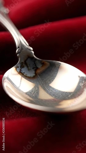 Close-up of silver spoon reflection on red velvet fabric