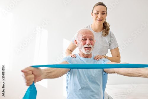 Obraz na plátně Doctor or nurse or physiotherapist caregiver exercise with senior woman at clini