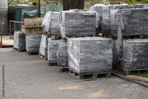 Stacked pallets covered in plastic wrap at construction site outdoors