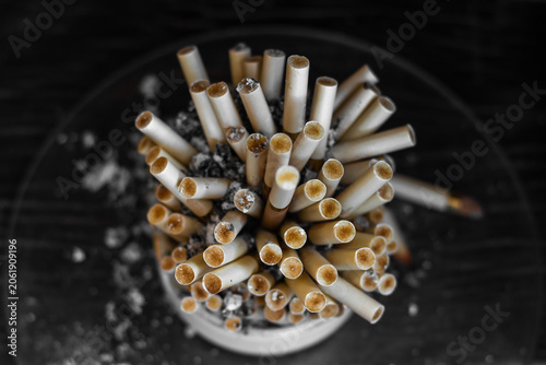 Close-up of cigarette butts in ashtray with scattered ash and debris