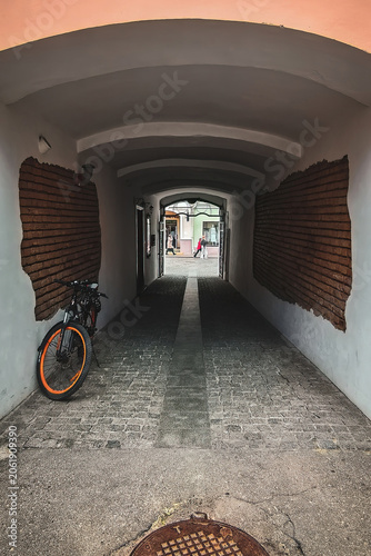 Bicycle parked in urban alleyway with brick wall and cobblestone path