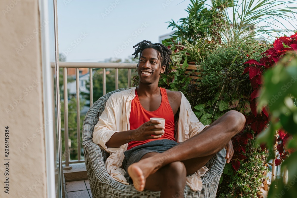 Fototapeta premium Relaxed man on balcony with coffee and plants in morning for lifestyle background and banner use
