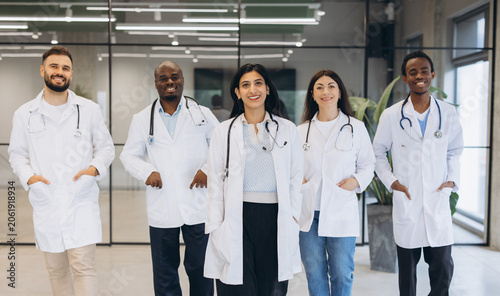 Diverse team of medical doctors standing in clinic, smiling at camera, showing unity and professional healthcare support