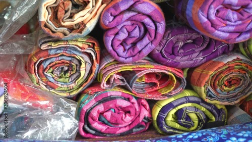 Close up of person choosing colorful woven loincloth fabric rolls in local shop.
