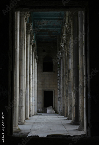 Abandoned Neoclassical Corridor with Columns and Dark Doorway
