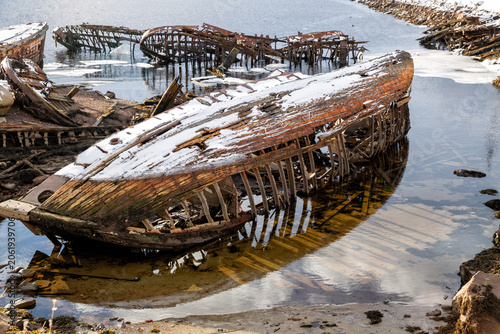 Cemetery of old boats on the shore of the Barents Sea in Teriberka at low tide. Murmansk Region, Russia