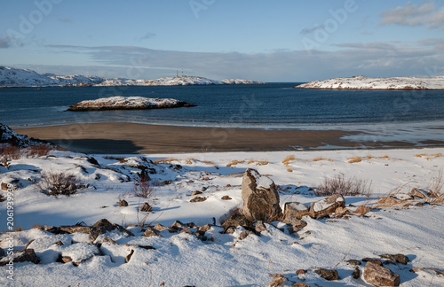 Winter seascape. Deserted snow-covered sandy beach of Teriberka Bay, Barents Sea. Murmansk Oblast, Arctic Circle, Russia