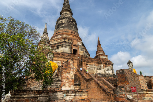 Two tourists ascend the ancient brick stairs of Wat Yai Chai Mongkhon in Ayutthaya, Thailand. This historic Buddhist temple complex is a popular destination for visitors.