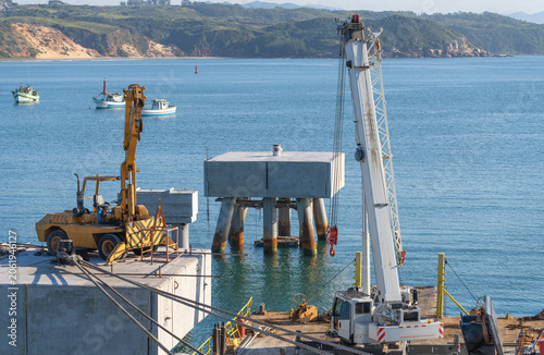 Foto Industrial development project on a scenic coastline, featuring large cranes, co