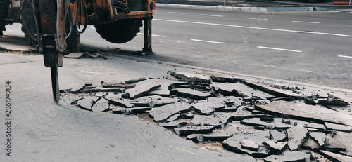 Photography Heavy machinery with a hydraulic hammer breaking up asphalt pavement, performing