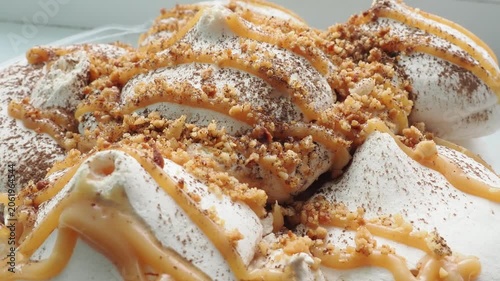 Meringue cake drizzled with caramel. A delicious dessert. A close-up of a multi-layered cake with nuts, cream, and almonds