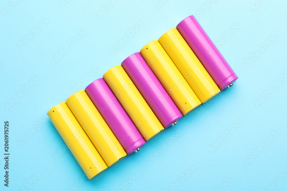 Fototapeta premium Many alkaline batteries on light blue background, flat lay