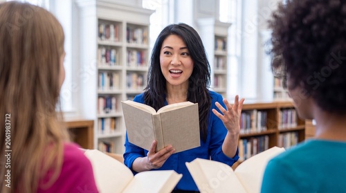 Woman reading aloud from book to friends in library