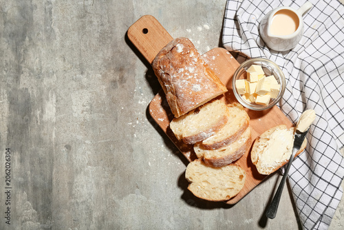 Billede på lærred Wooden board with sliced bread, butter and jug of cream on grey grunge backgroun