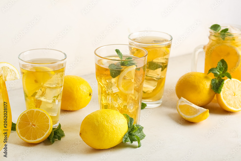 Fototapeta premium Glasses of lemon ice tea with mint and citrus fruits on white background, closeup