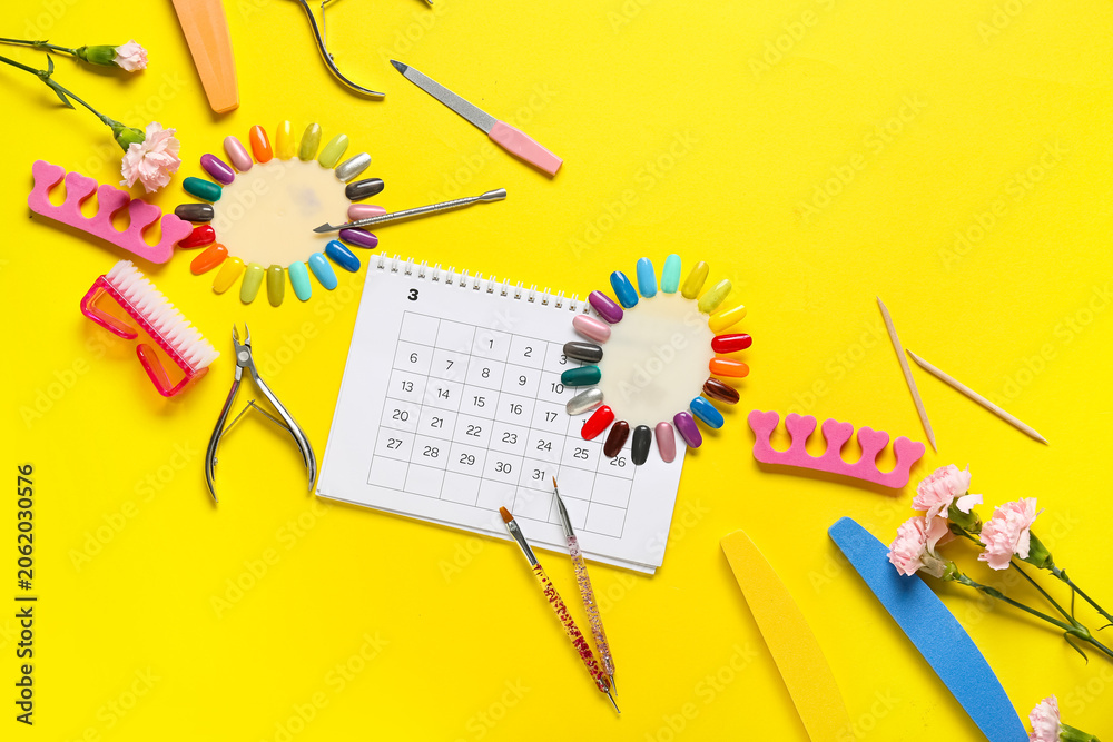 Obraz premium Calendar with nail masters supplies and carnation flowers on yellow background